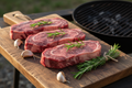 Grass-fed NY strip steaks with herbs on wooden board