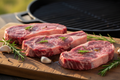 Grass-fed chuck eye steaks with herbs on wooden board