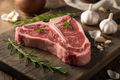 Grass-fed T-bone steak with herbs on wooden board